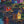 Load image into Gallery viewer, Colours of Home by Adam Young — colourful saltbox homes and fishing stages on a rocky hillside above a harbour reflecting red and gold light
