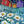 Load image into Gallery viewer, Daisies by Adam Young, original acrylic painting, 20 by 48 inches, white daisies and blue blossoms before a picket fence and red, blue and purple saltbox homes
