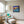 Load image into Gallery viewer, Forget Me Nots by Adam Young framed beside an armchair and reading lamp

