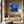Load image into Gallery viewer, Little Outhouse by Adam Young on a wood-panelled wall above a stone bench
